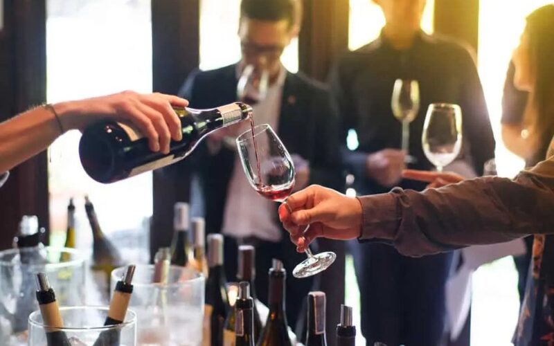 One person pouring a glass of red wine for someone else