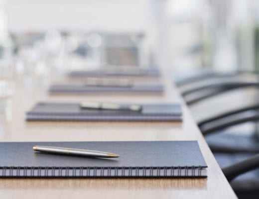 Neatly laid stationary on conference table.