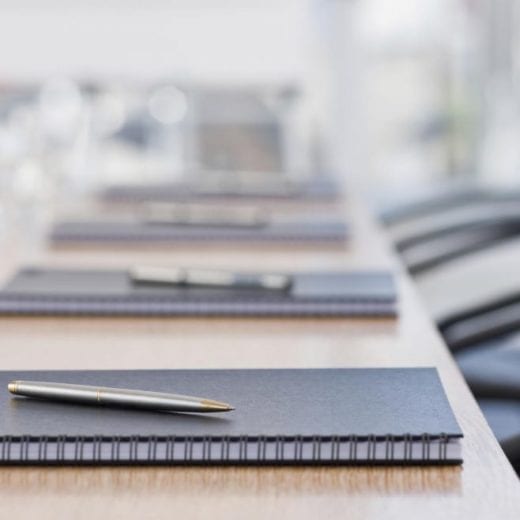 Neatly laid stationary on conference table.