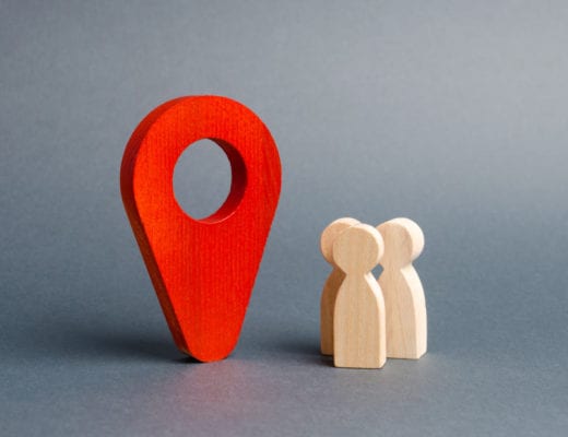 Location icon and small people wooden figures.