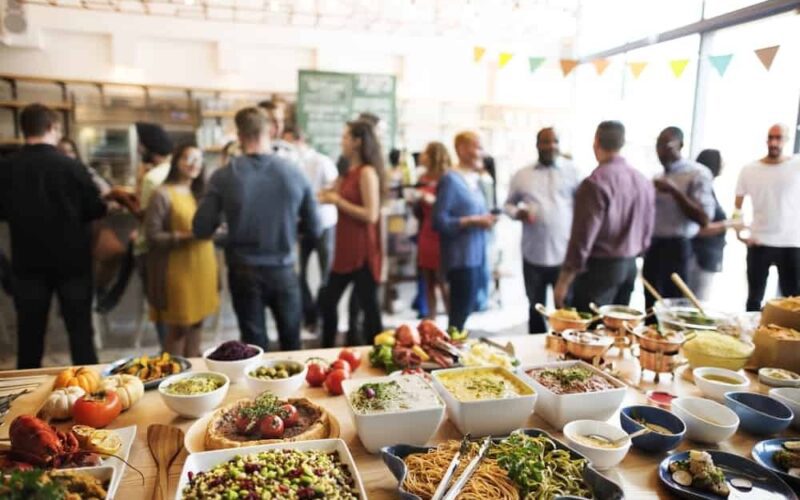 Groups of people talking in a room with a buffet